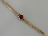 un gros plan d'un bracelet en or orné d'une pierre rouge