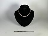 un collier à chaîne en argent exposé à côté d'un mannequin noir