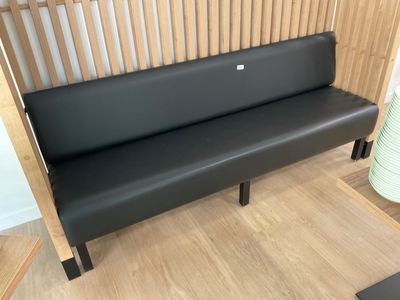a black bench in a room with a wooden wall behind it