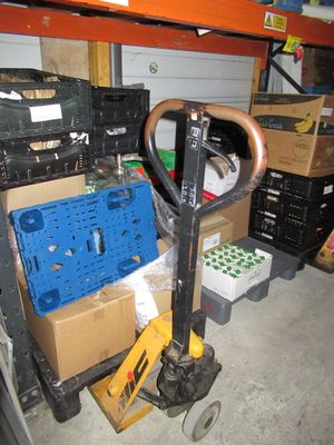 a fork and a cart in a garage with boxes on the floor