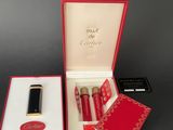 an open red box with a lipstick and a lipstick brush in it