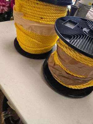 deux bobines de corde jaune posées sur une table, avec des fleurs en arrière-plan