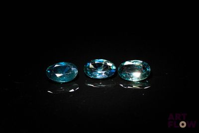 un ensemble de trois pierres précieuses de topaze bleue posées sur une surface noire