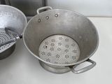 two pots and a strainer on the counter