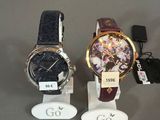 trois montres sont exposées sur un présentoir, accompagnées d'étiquettes
