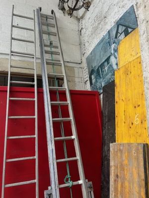 deux échelles appuyées contre un mur rouge