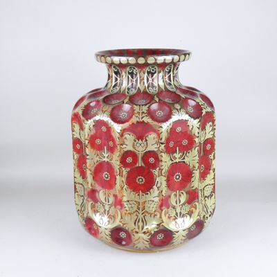 a red and gold vase sitting on a white surface