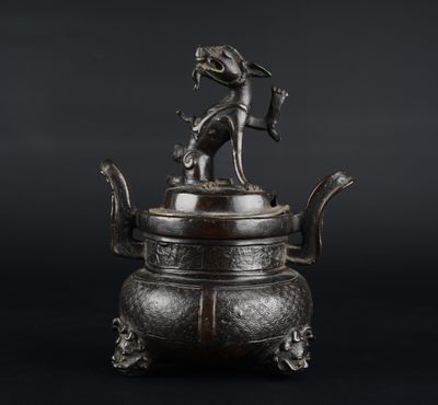 une vieille théière en bronze surmontée d'un chien