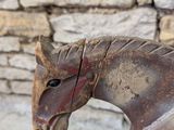 a wooden horse that is sitting next to a brick wall