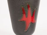 a black and red cup with a red leaf on it