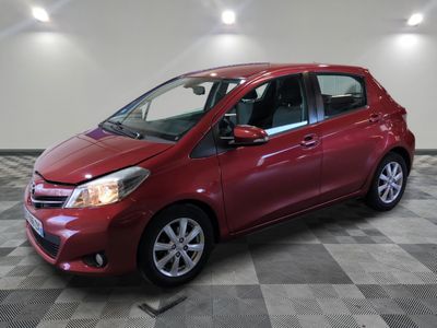 une Toyota Yaris rouge garée dans une pièce au sol en damier