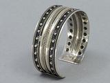 a close up of a silver bracelet with black dots on it