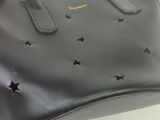 black leather handbag with stars on it on a white surface