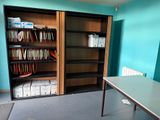 a room with a table, bookshelf, and a bookcase