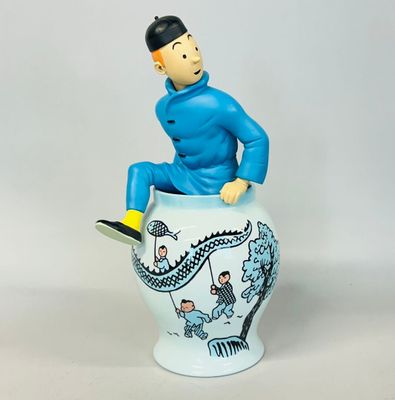 a figurine of a man sitting on top of a vase