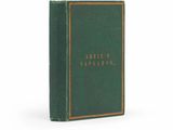 un livre vert orné de lettres dorées, posé sur une surface blanche