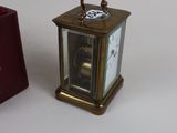 a small clock sitting next to a small red box