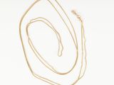 a gold necklace with a gold chain and a white background