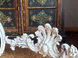 a large ornate mirror on the floor next to a cabinet