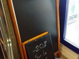 a chalk board with a price written on it in front of a window