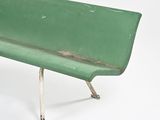 a green bench that is sitting on a white surface