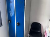 a blue locker next to a black chair in the corner of a room