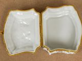 a close up of a white and gold box on a brown surface
