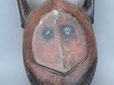 un masque marron muni de cornes sur un fond blanc