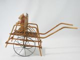 a small teddy bear sitting in a wooden cart