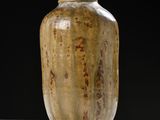 a brown vase sitting on a table with a black background