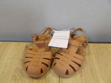 tan leather sandals with straps and buckles on a wooden surface