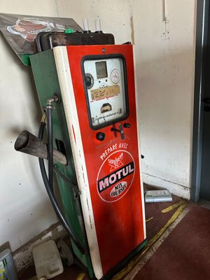 a red and green gas pump next to a white wall