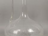 une bouteille en verre transparent munie d'une anse, posée sur une table