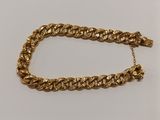 un bracelet à chaîne en or avec un fermoir sur fond blanc