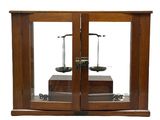 une vitrine en bois surmontée de deux balances
