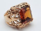 une image représentant une bague en or avec une pierre orange au centre