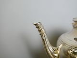 a silver tea pot sitting on a table next to a white wall