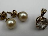 a pair of pearl and diamond earrings on a white surface