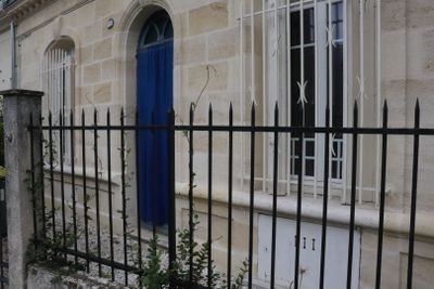 a blue door on a stone building behind a black fence