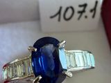 une photo d'une bague sertie d'un saphir bleu et de diamants, dans un écrin