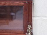 a small wooden cabinet with a glass door on top of it