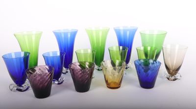 plusieurs vases en verre de différentes couleurs sont alignés sur une surface blanche