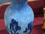 un vase bleu posé sur une table rouge, à côté d'autres objets