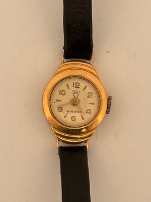a gold watch on a black strap on a white surface