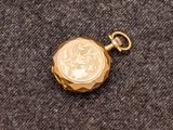 un gros plan d'une montre de poche en or sur laquelle repose une pièce de monnaie