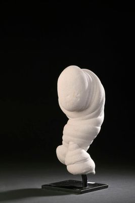 a white sculpture on a black base with a black background