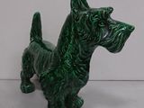a small green dog figurine sitting on a white surface