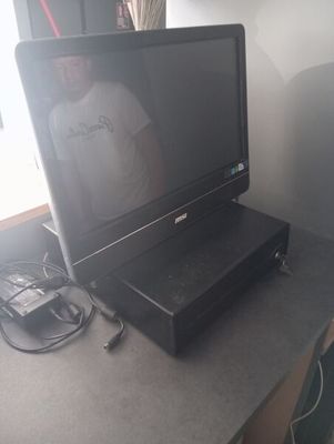 un ordinateur portable posé sur un bureau, avec un homme en arrière-plan