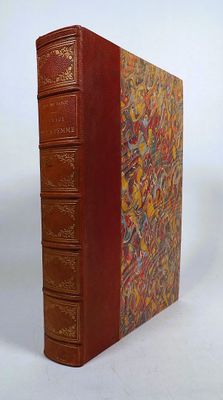 an old book with a red cover sitting on top of a white surface