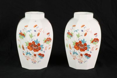 pair of white vases with floral designs on them against a black background